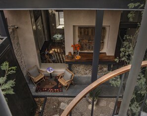 Un interior espacioso con techo alto, una zona de estar con sillas y mesa, chimenea y vistas al exterior.