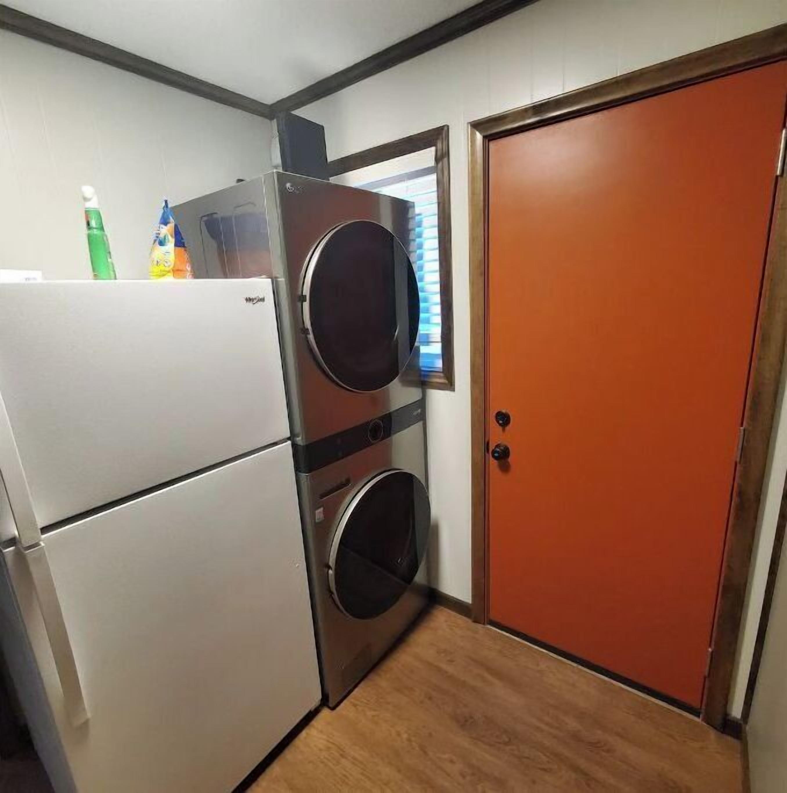 A compact kitchen with a white refrigerator, a washing machine, and a wooden door.