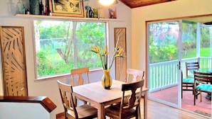 Un coin repas avec une table et des chaises en bois, un vase rempli de fleurs et un ventilateur de plafond.