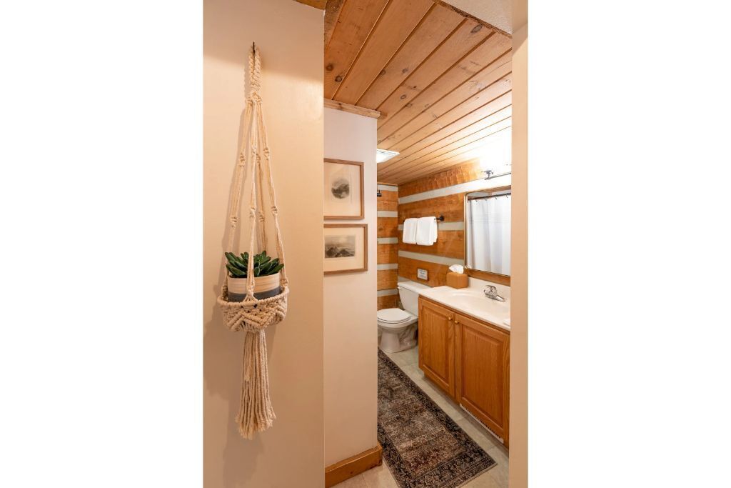 Een kleine badkamer met houten kastjes, een wastafel en een toilet.