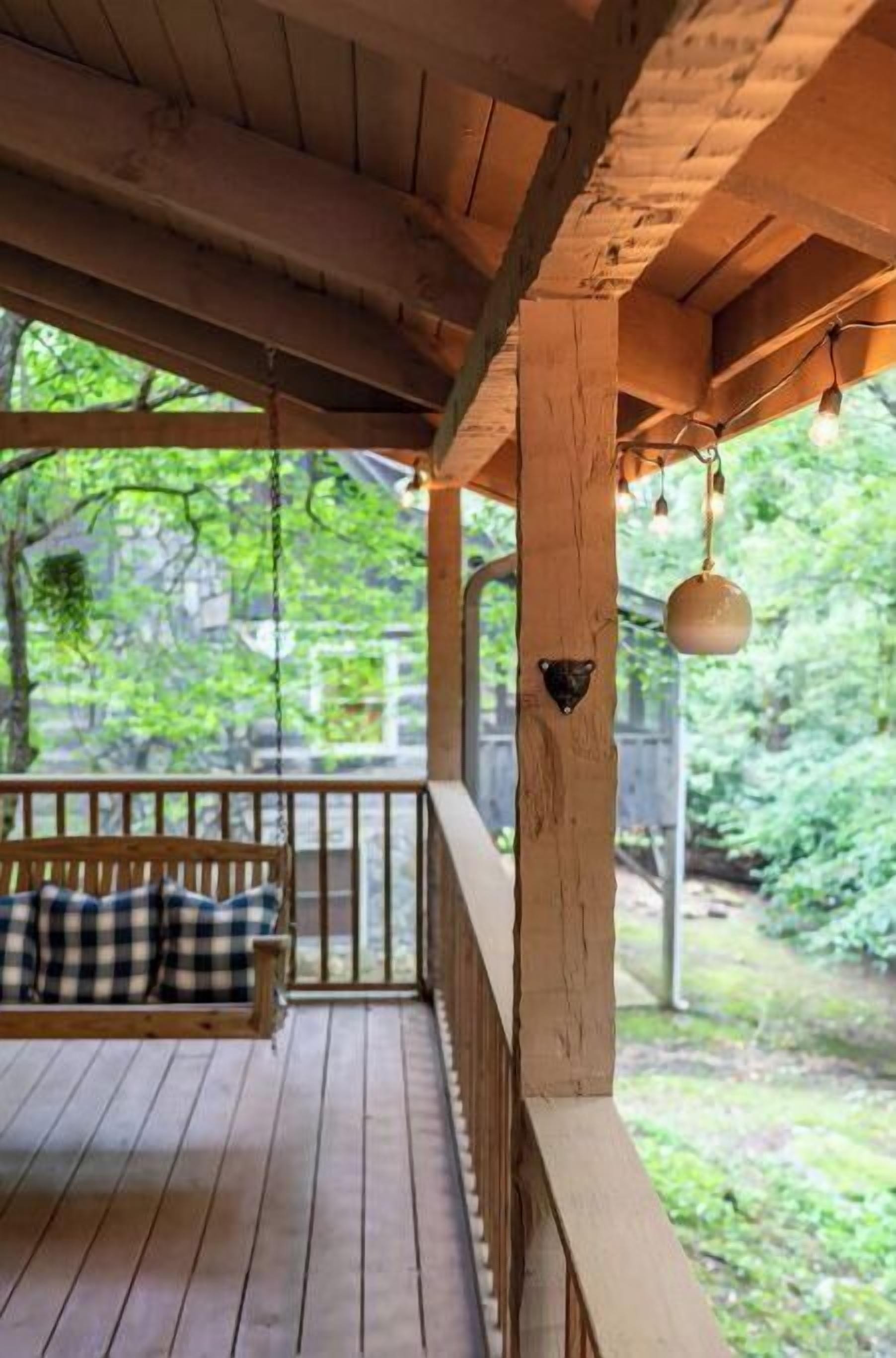 A wooden deck with a bench and a hanging light fixture.
