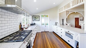 Una cocina moderna con estufa a gas, armarios blancos y piso de madera.