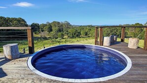 Un jacuzzi en una terraza de madera con vistas a un paisaje verde.