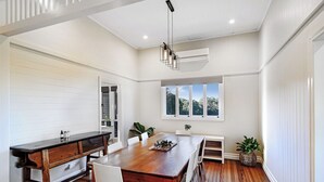 Un comedor amplio con una mesa de madera, sillas blancas y plantas en macetas.