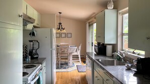 A modern kitchen with a central island, a dining area with a chandelier, and a view of the outdoors through a window. - Charming City Home with Professional WFH Setup & AC (Bellevue)