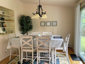 Uma sala de jantar com um candelabro, uma planta em vaso e obras de arte emolduradas na parede.