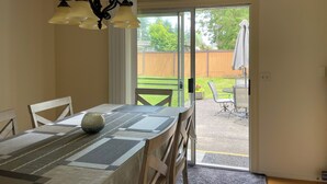 A dining area with a table set for four, a chandelier, and a sliding glass door leading to an outdoor patio. - Charming City Home with Professional WFH Setup & AC (Bellevue)