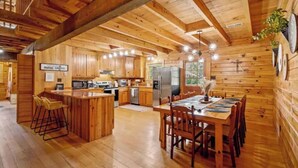 Interior de una cabaña de madera con cocina, comedor y barra.