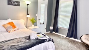 A neatly arranged bedroom with a bed, bedside lamp, and a small plant on a nightstand.