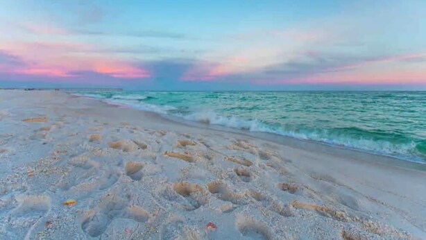 Una playa con cielo despejado y mar tranquilo.