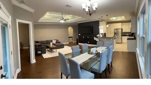 Una sala de estar moderna con sofá, televisor y comedor con sillas y una mesa.