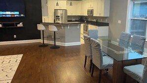 Una cocina moderna con una isla central, taburetes de bar y una mesa de comedor con sillas.