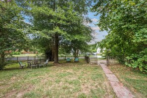 Un parc doté d’un chemin pavé, de bancs et d’un grand arbre.