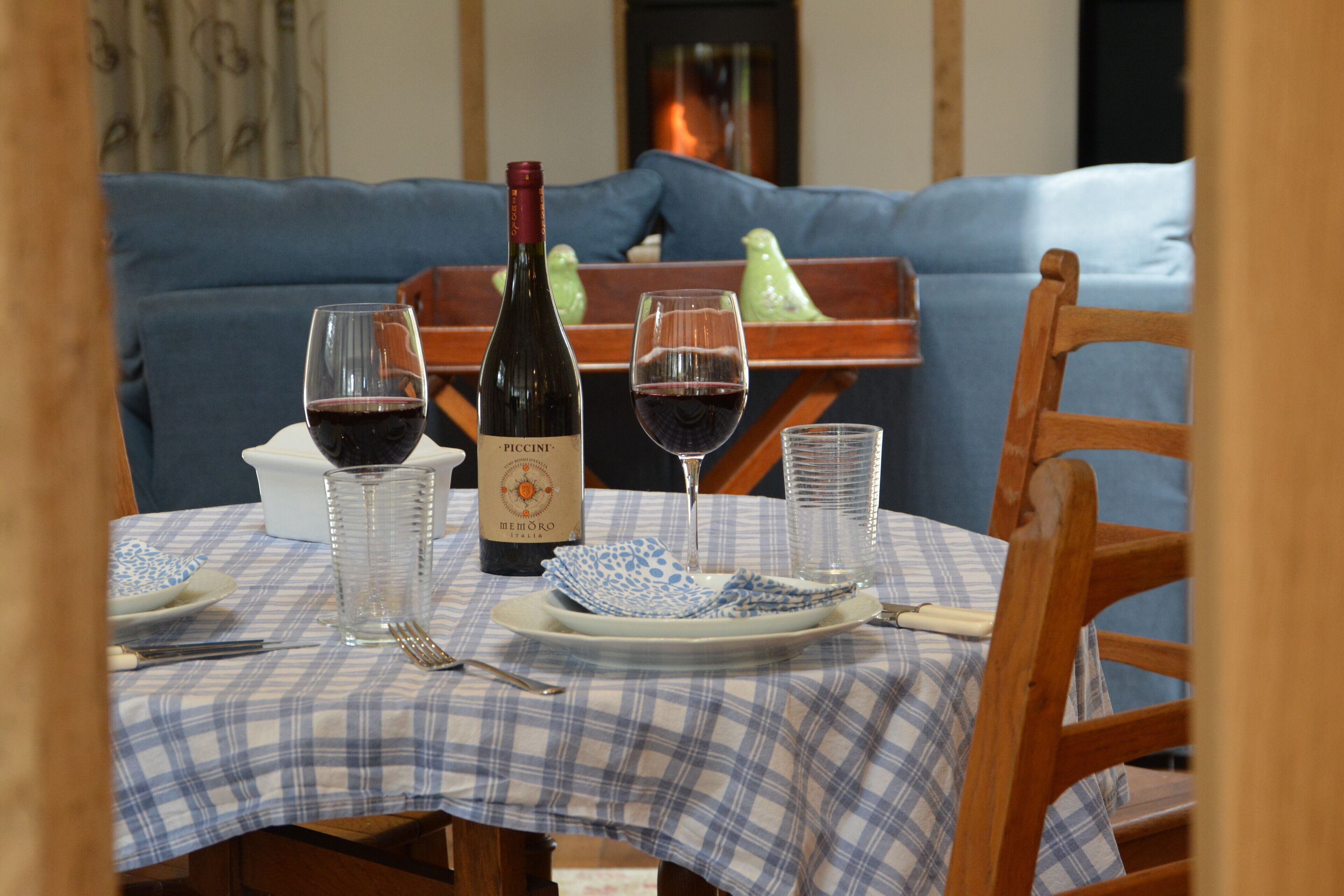 A dining table set with a bottle of wine, glasses, plates, and cutlery.