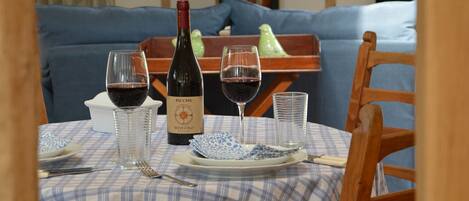 A dining table set with a bottle of wine, glasses, plates, and cutlery.