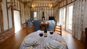 A cozy dining area with a checkered tablecloth, wooden chairs, and a fireplace. - Bird Cottage, Burgh (Woodbridge)