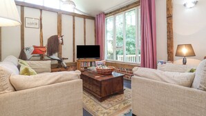 A cozy living room with two sofas, a wooden coffee table, a television, and a bookshelf.