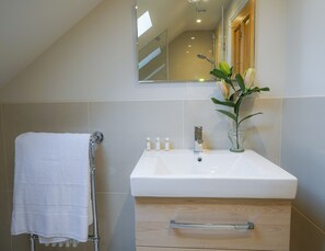 A bathroom with a white sink, a towel rack, a mirror, and a plant. - 10 Church Walk, Aldeburgh (Aldeburgh)