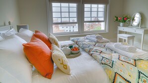 A neatly made bed with pillows, a tray with breakfast items, and a view of buildings through the window. - 10 Church Walk, Aldeburgh (Aldeburgh)