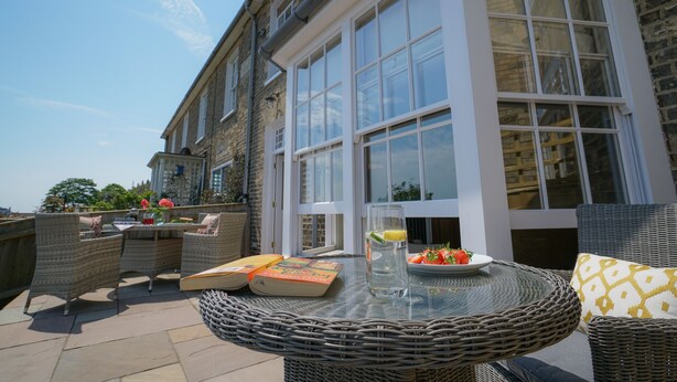 A patio with wicker furniture, a glass table, and a book. - 10 Church Walk, Aldeburgh (Aldeburgh)