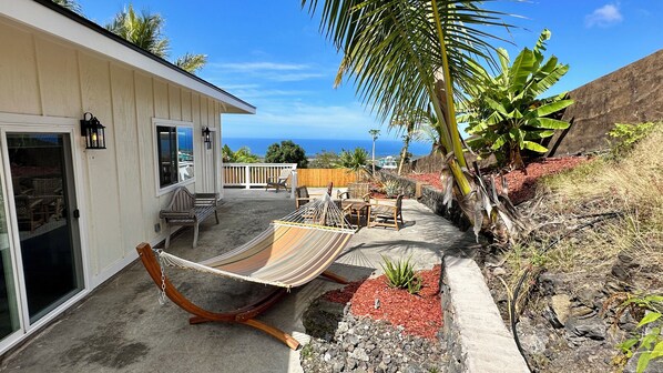 A house with a patio area featuring a hammock, outdoor furniture, and a view of the ocean.