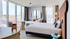 Habitación de hotel moderna con una cama grande, un escritorio y vistas a la ciudad.
