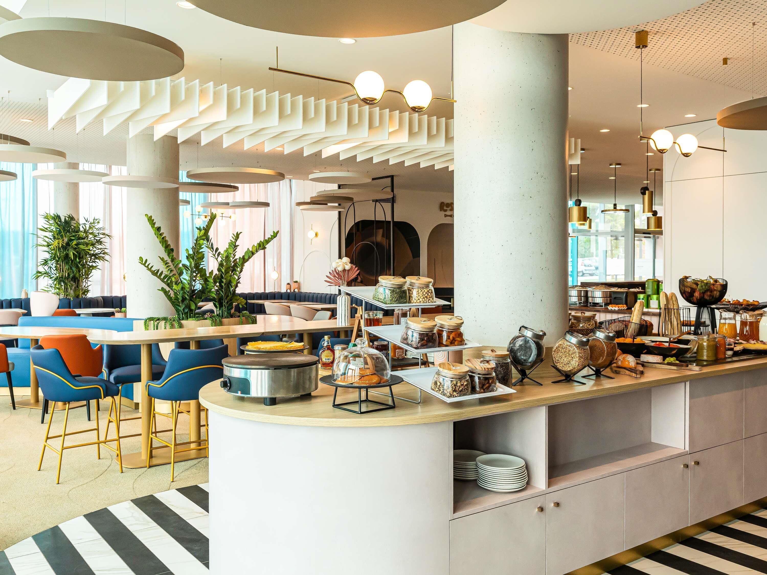 A modern cafe with a central bar area, seating arrangements, and a variety of food and drink options.
