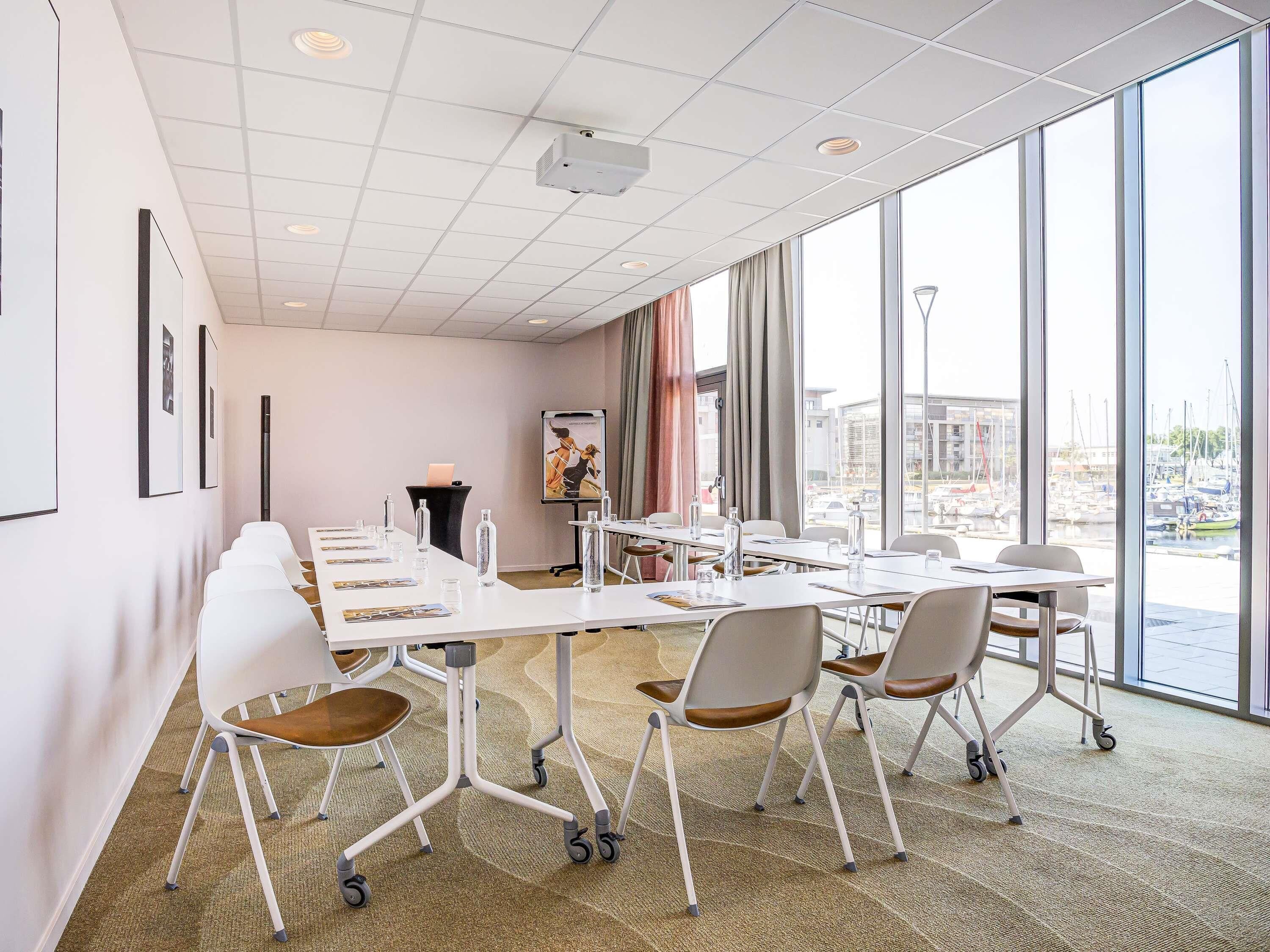 A conference room with white tables, chairs, and a projector.