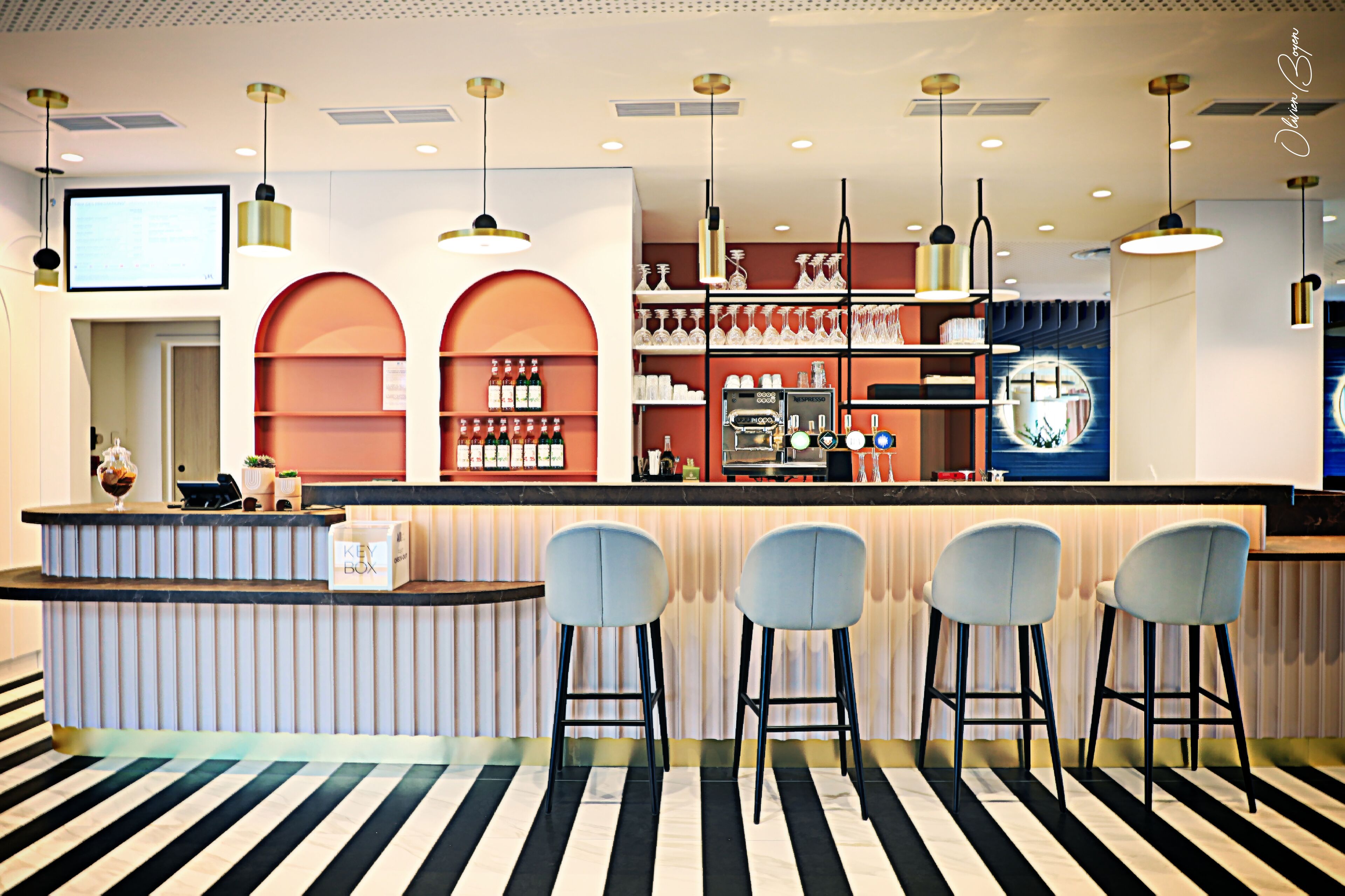 A bar area with a counter, bar stools, shelves with bottles, and a television screen.