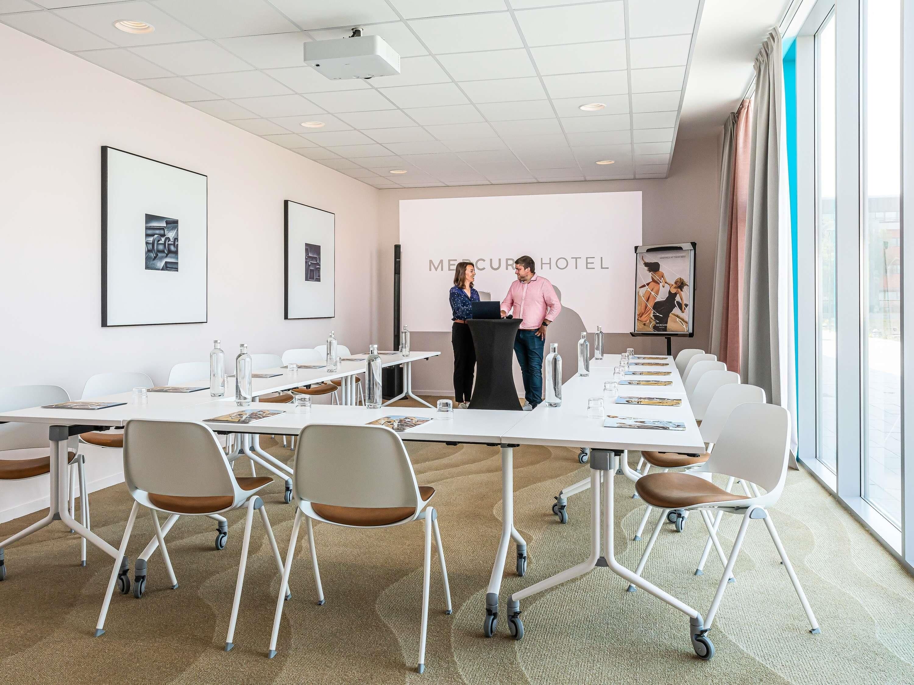 A conference room with a long table, chairs, and a podium.