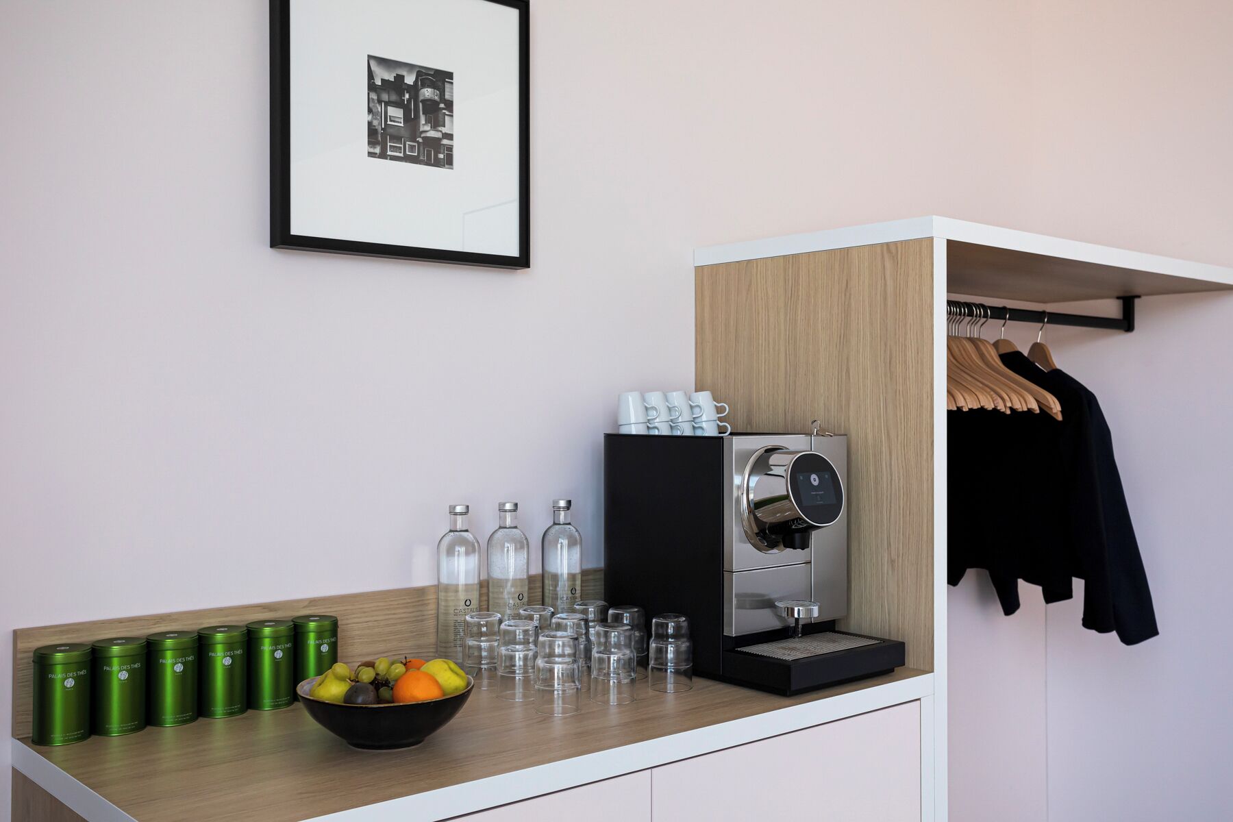 Eine Küchenzeile mit einer Kaffeemaschine, einer Obstschale und einem Kleiderständer.