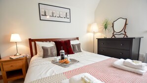 A neatly arranged hotel room with a bed, bedside tables, a dresser, and a framed picture on the wall. - Three Chantry Barns, Orford (Woodbridge)