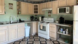 A kitchen with light wooden cabinets, a white stove, a microwave, and a sink. - High Peaks Haven is in the heart of Adirondack. Come enjoy with famil (Keeseville)