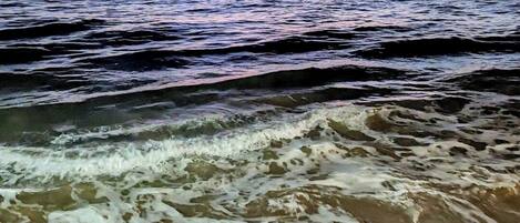 Una playa con olas y un atardecer.