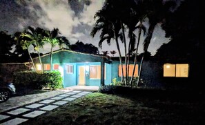 Una casa con fachada azul, un porche delantero y un camino de entrada pavimentado.