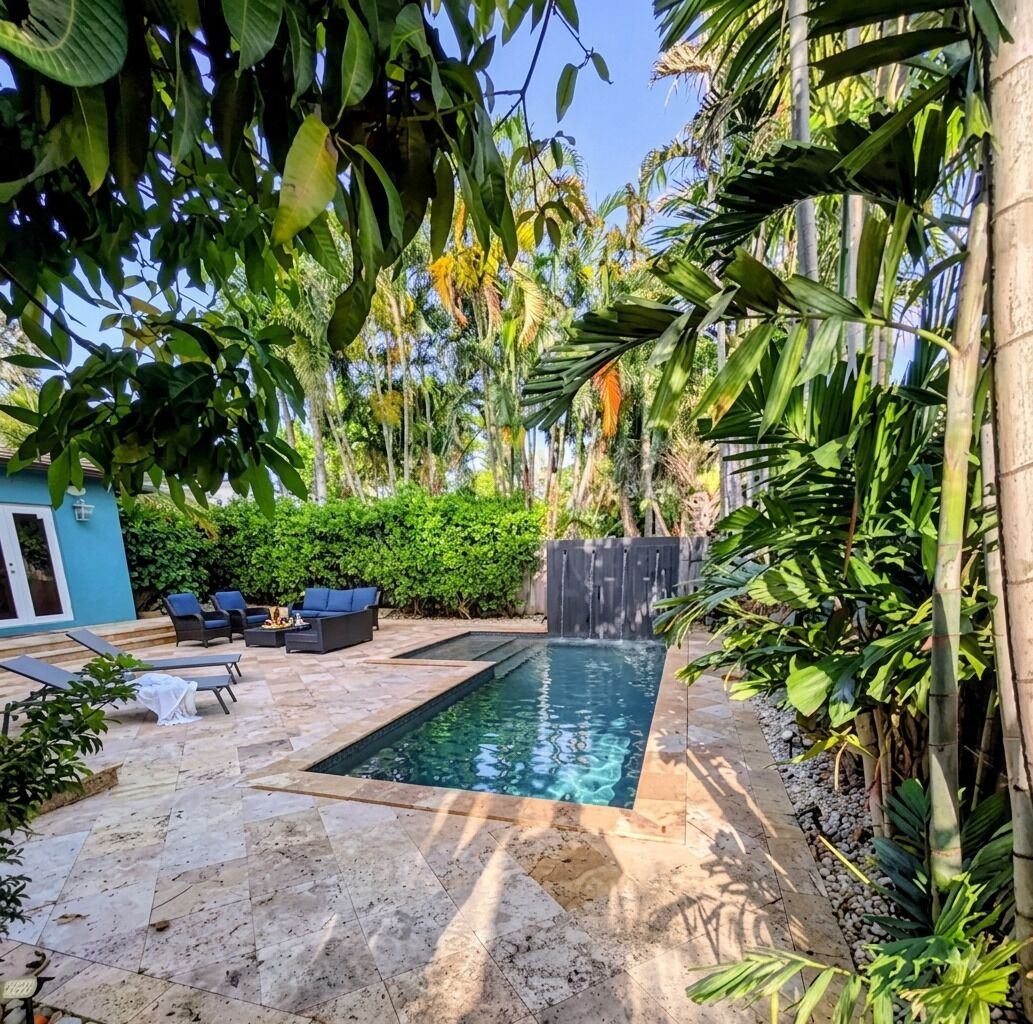 Ein Swimmingpool mit Wasserfall, umgeben von üppiger tropischer Vegetation und einem blauen Gebäude.