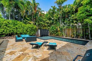 A pool area with lounge chairs, a waterfall feature, and lush tropical vegetation.