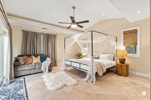 A bedroom with a four-poster bed, a ceiling fan, a large window with blinds, a sofa with cushions, and a rug. - #1 Family Oasis/Htd SW Pool/3BR/10mins to all/No Car Rqd/New Pics/All Updated (Fort Lauderdale)