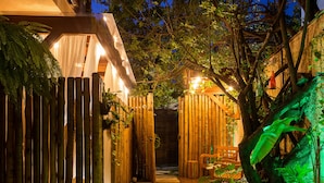 A nighttime garden pathway with wooden fencing, a wooden bench, and artificial grass. - Casa dAroeira - Condomínio Residencial de Flats (São Sebastião)