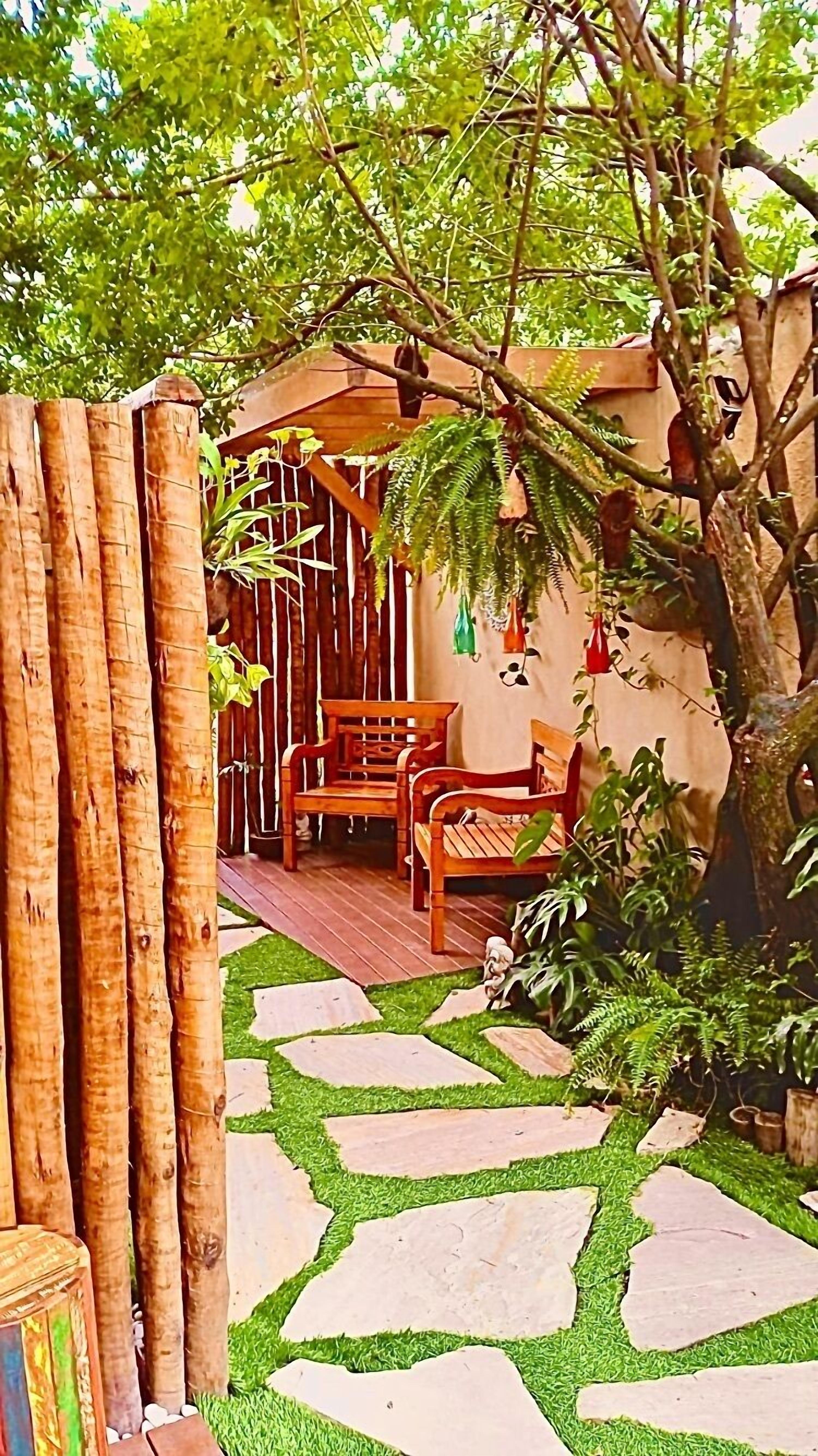 A wooden outdoor seating area with a stone pathway leading to a wooden structure.