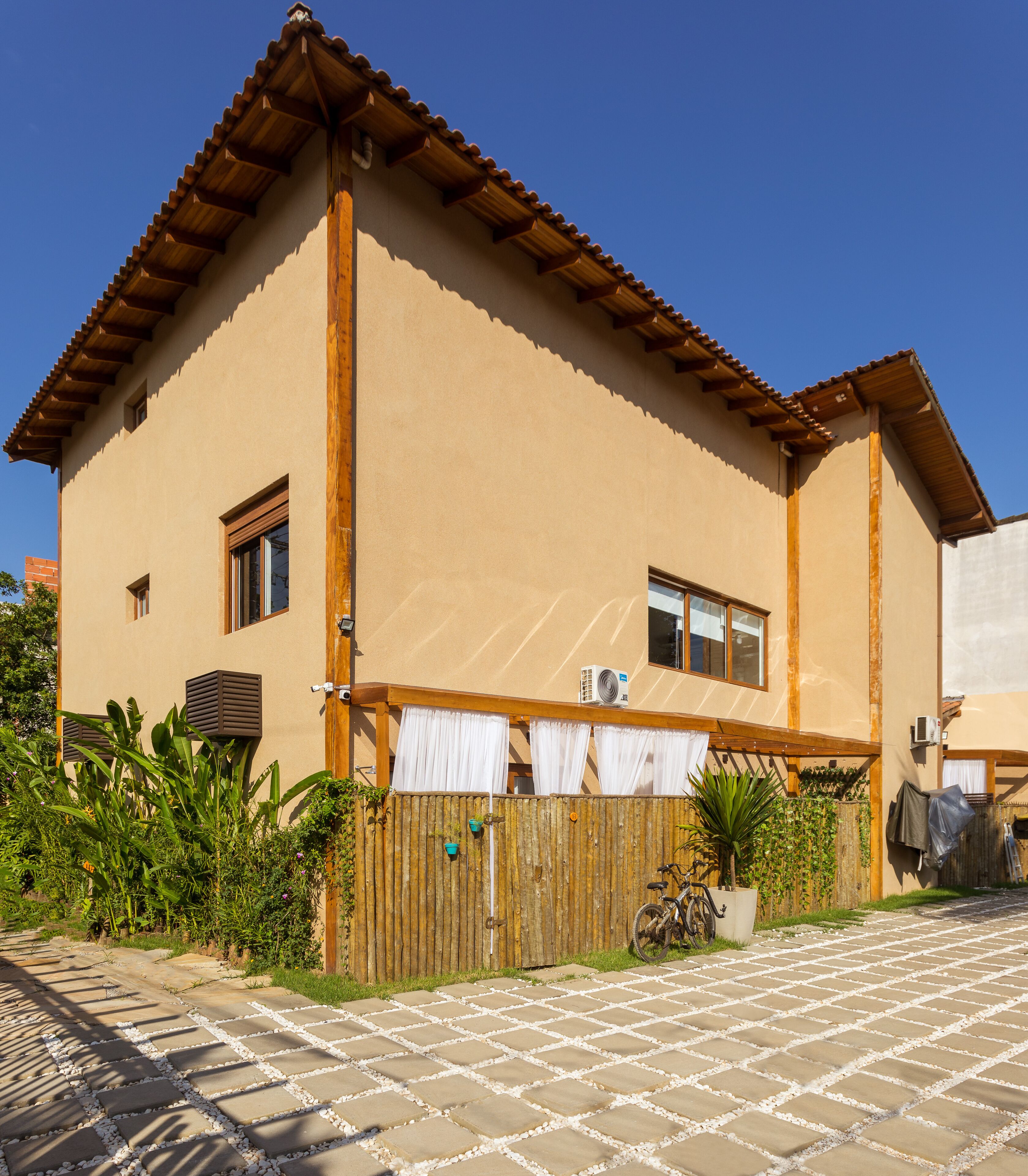 A two-story house with a tiled patio, wooden fence, and potted plants.