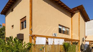 A two-story house with a tiled patio, wooden fence, and potted plants.