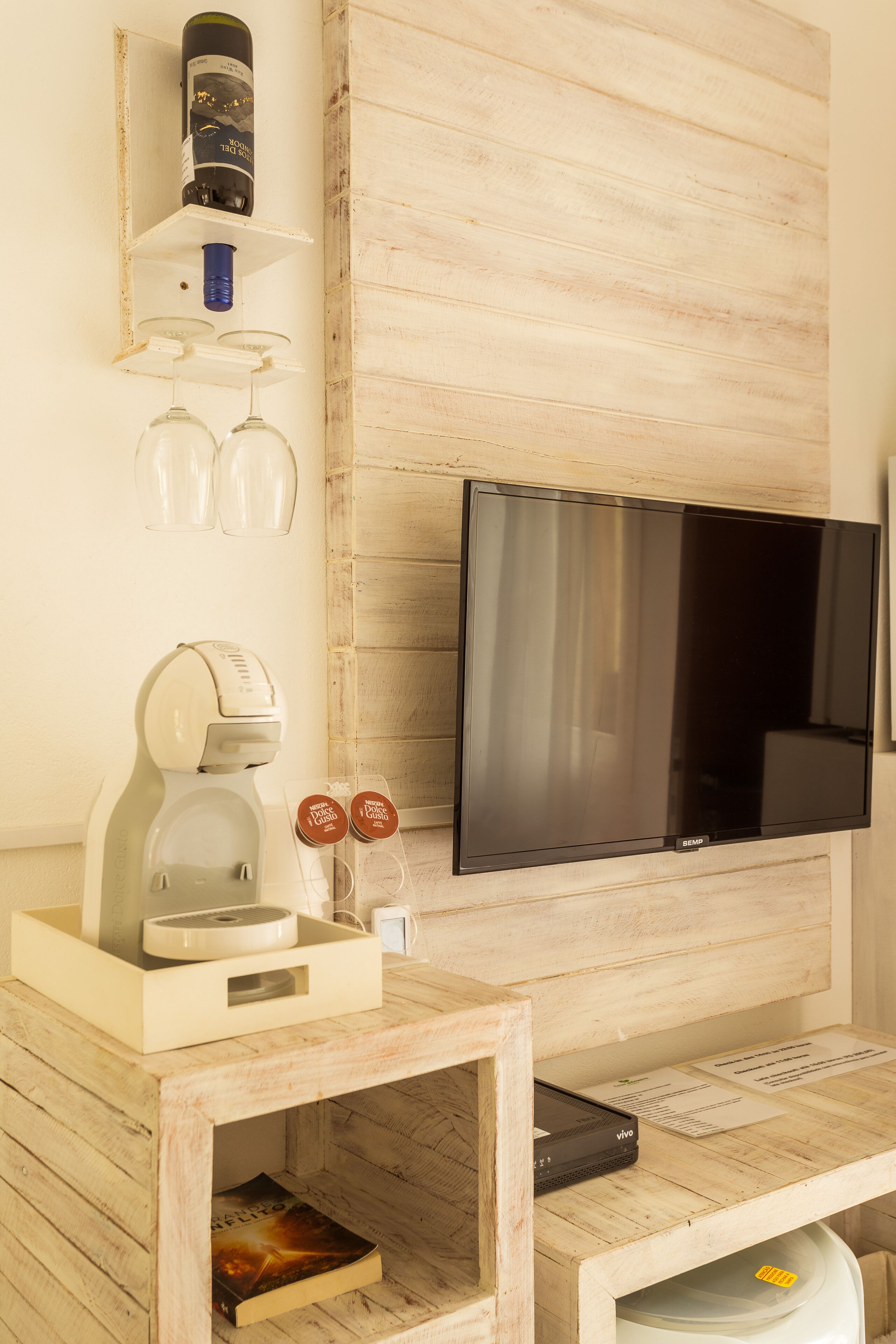 Una stanza con parete in legno, TV a schermo piatto, macchina del caffè e un piccolo tavolo con un libro.