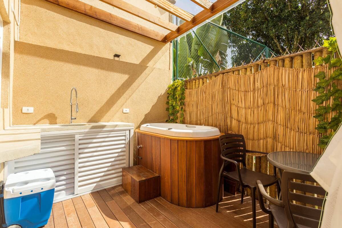 Un bain à remous avec des chaises en bois, une table et un mur en bambou.