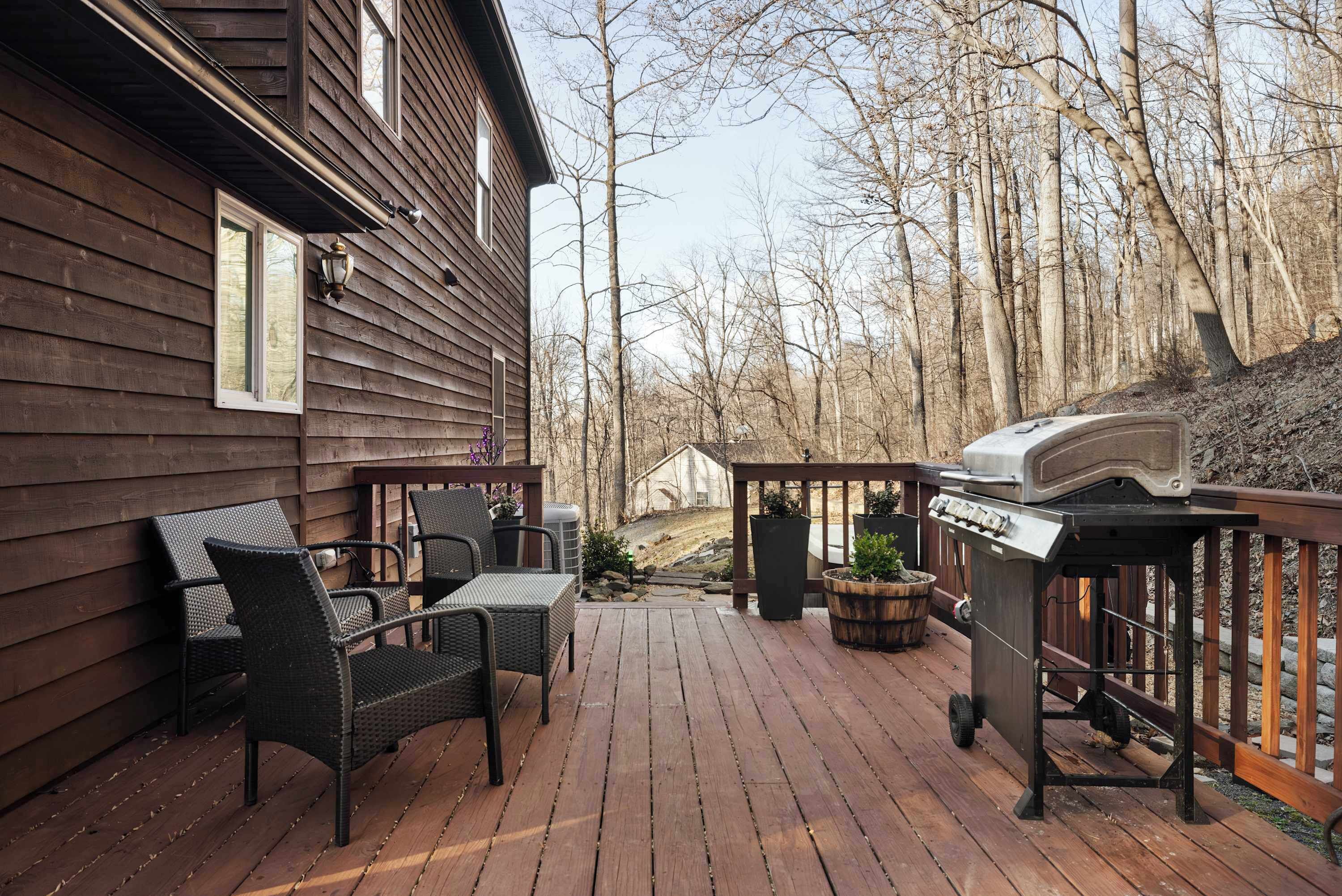 Una terraza de madera con mobiliario exterior y una parrilla.