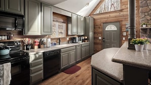 Una cocina con armarios de madera, microondas, estufa y lavavajillas.