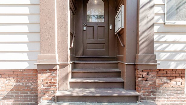 A front entrance with a brown door, steps leading up to it, and a mailbox on the wall. - Charming 2 bedroom near Central Square!  (Cambridge)