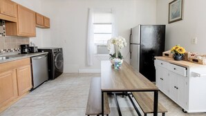 A modern kitchen with wooden cabinets, a black refrigerator, a dishwasher, and a countertop with a coffee maker and toaster. - Charming 2 bedroom near Central Square!  (Cambridge)
