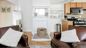 A modern living room with leather sofas, a fireplace, and a kitchen area with a microwave and stove. - Charming 2 bedroom near Central Square!  (Cambridge)