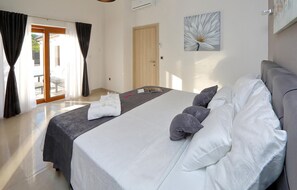 Relax in a spacious room with a large bed, white linens, and a wall-mounted artwork.